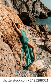 여자 녹색 드레스 바다. 긴 민트 드레스를 입은 여자는 화창한 날에 바위와 해변에서 포즈. 푸른 하늘 배경에 자연에 소녀. 스톡 사진