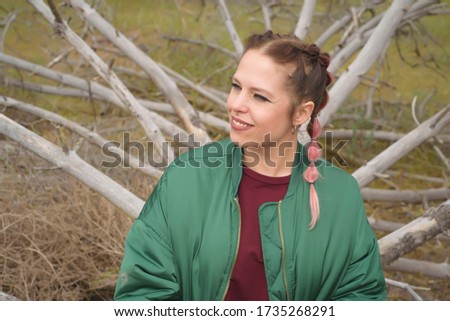 Woman in a green and flowery landscape sitting on a dry trunk and with the branches behind as a throne. Idyllic place in spring.