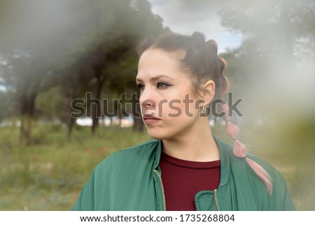 Woman in a green and flowery landscape very serious and sad. Idyllic place in spring.