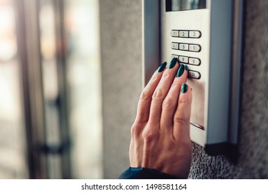 Woman with green nail polish typing pin code to unlock smart digital door lock