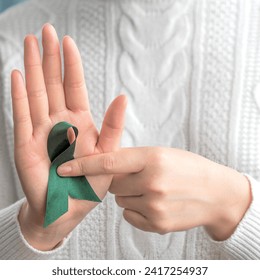 A woman with green ribbon. Hands holding green ribbon. Healthcare and world cancer day concept - Powered by Shutterstock