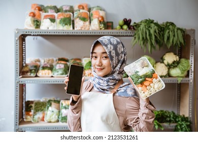 Woman Greengrocer Showing Vegetables And Showing A Phone Screen