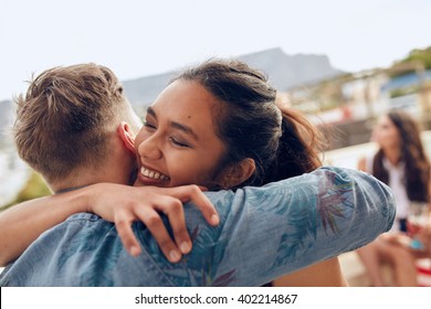 Woman greeting her boyfriend and embracing. Young woman welcoming her friends at party. Young friends arriving at rooftop party.