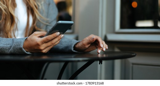 Woman in grey jscket using smartphone, close up photo.  - Shutterstock ID 1783913168