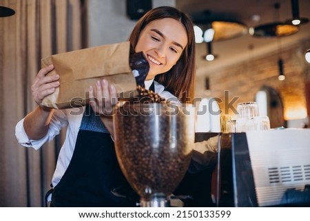 Woman grinding coffee in coffee machine