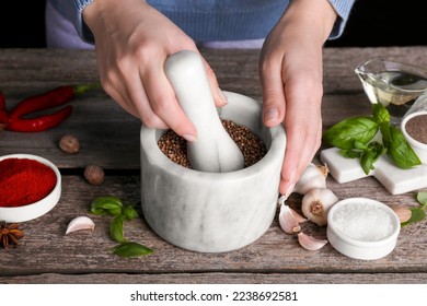 Woman grinding coriander at wooden table, closeup - Powered by Shutterstock