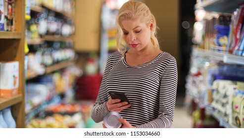 Woman At The Grocery Store Looking Up Nutrition Facts On Smartphone