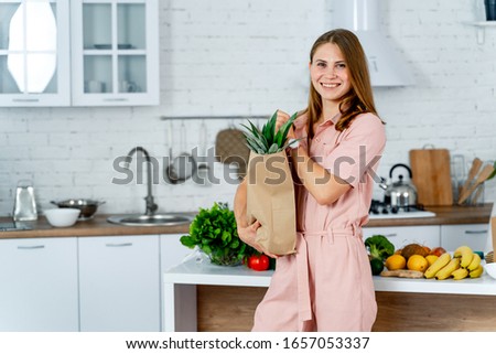 woman with the grocery store packet in the hands. Kitchen background. Young woman with healthy food.