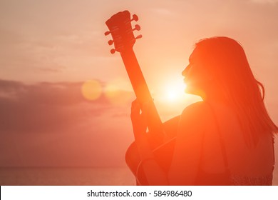 Woman And Guitar With Sunset Silhouette