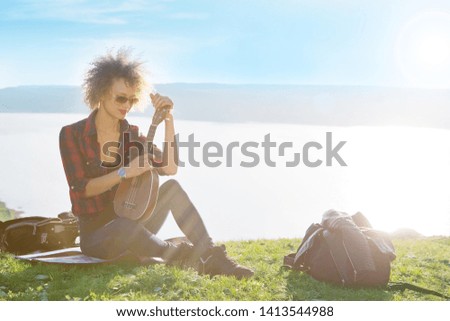 Woman with guitar ukulele in the mountains, amazing landscape, stunningly beautiful nature, mountains, sunset. Lifestyle.