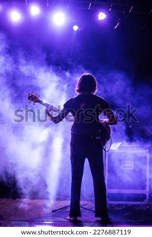 woman guitarist performing with lights and smoke