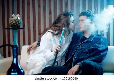 Woman with guy hookah, blow smoke from tobacco, blue shisha background.