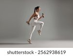 Woman in gym clothes exercising with dumbbells on grey background