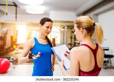 Woman In Gym, Personal Trainer, Consultiing Plan On Clipboard