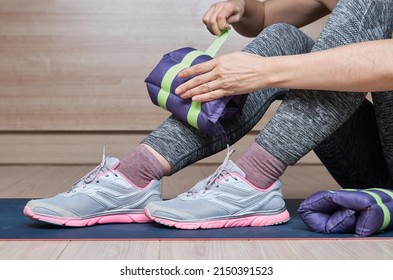 Woman At Gym Putting Ankle Weights.