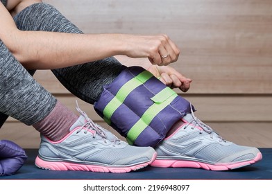 Woman At Gym Putting Ankle Weights.