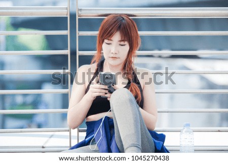 woman at the gym relaxing and listening to music using a mobile phone and earphones