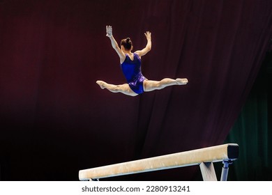 woman gymnast exercise split jump in balance beam gymnastics, sports summer games  - Powered by Shutterstock