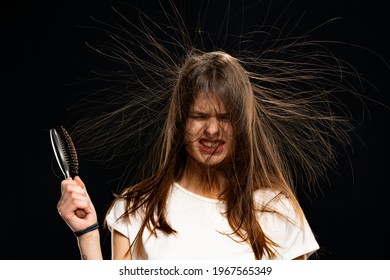 Woman With A Hair Brush And Static Hair On Black Background.