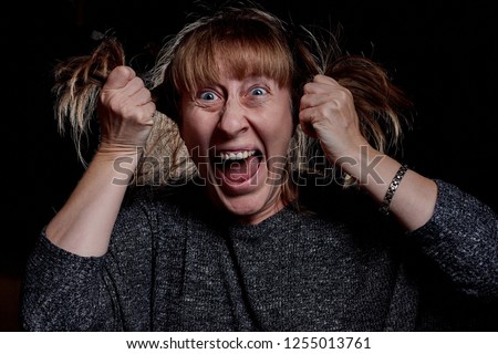 Woman with hair curlers and with funny emotion on the face. Anger, resentment, pain. Girl don't like her hair. Photoshoot in dark key