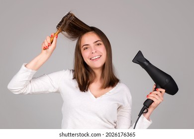 Woman with hair dryer. Beautiful smiling girl with straight hair drying hair with professional hairdryer.