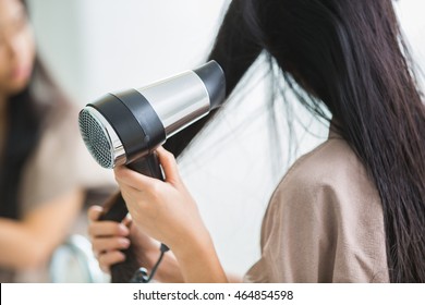 Woman With A Hair Dryer To Heat The Hair.