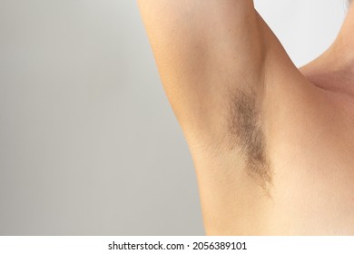 Woman hairy unshaved armpit holding arm aside on white background with copy space