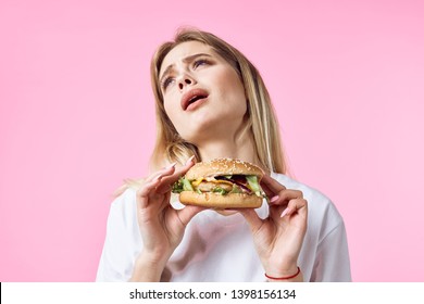 A woman with hamburgers tilted her head back against a pink background