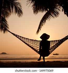 Woman In Hammock Enjoying Sunset On The Beach