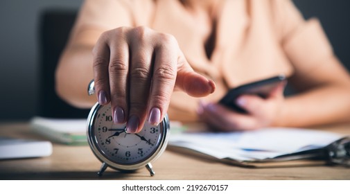 Woman Hand  Alarm Clock To Stop Time In Working Table