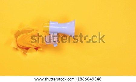 Woman hand arm hold megaphone isolated through torn yellow background Copy space advertisement place for text or image workspace mock up Hot news announce discounts sale hurry up communication concept
