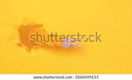 Woman hand arm showing victory sign v-sign isolated through torn yellow wall background studio. Copy space advertisement place for text or image promotional content Advertising area workspace mock up