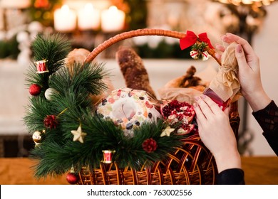 Woman Hand Arranging Christmas Goods In A Basket. Festive Holiday Food Gift Concept