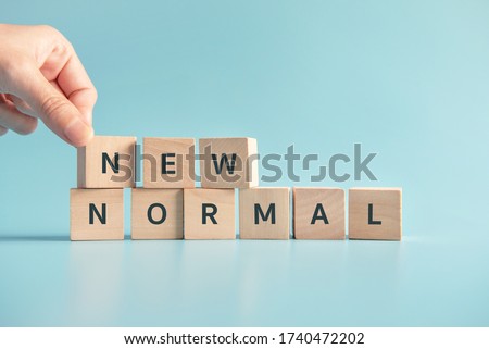 Woman hand arranging wooden cubes with NEW NORMAL word. Adapting to new life or business post-lockdown after coronavirus pandemic. Business with social distancing personal hygiene.