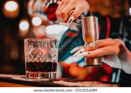 woman hand bartender making negroni cocktail. Negroni classic cocktail and gin short drink with sweet vermouth, red bitter liqueur in bar