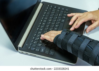 Woman hand in black orthosis is working on computer. A freelancer with one broken wrist typing on laptop computer on keyboard. - Shutterstock ID 2233328241