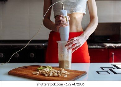 Woman With Hand Blender Making Sweet Banana Protein Powder Milkshake Smoothie. Protein Shake After Workout. Sport Nutrition Diet After Gym. Healthy Lifestyle