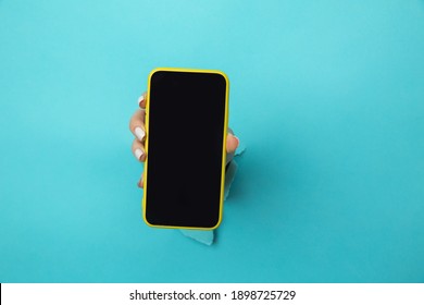 Woman hand in the blue paper hole holding smartphone