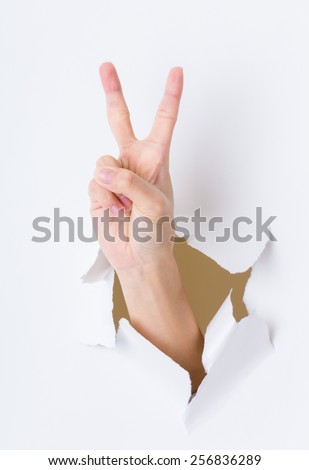 Woman hand breaking through paper wall pointing with the two finger