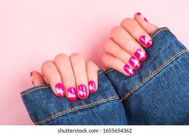 Woman hand and bright manicure in denim jacket isolated pink background 