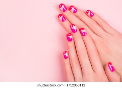 Woman hand and bright manicure isolated pink background 