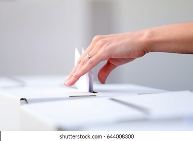 Woman hand casts a ballot as she votes for the local elections at a polling station. Focus on hand.