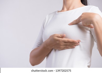 Woman hand checking lumps on her breast for signs of breast cancer on gray background. Healthcare concept. - Shutterstock ID 1397202575