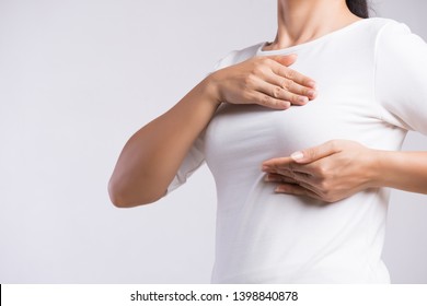Woman hand checking lumps on her breast for signs of breast cancer on gray background. Healthcare concept. - Shutterstock ID 1398840878
