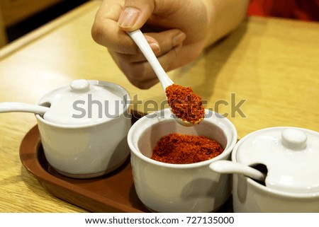 Woman hand Chili powder in a small jar. Used for cooking and adding a national car of food placed on a table in a restaurant.