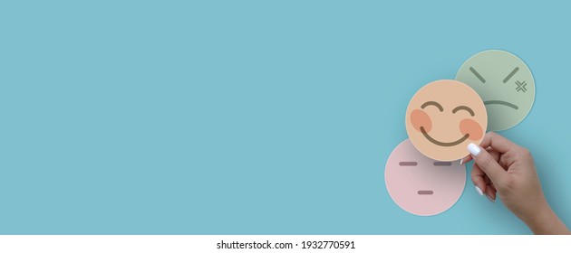 Woman hand choosing happy smile face paper cut, feedback rating and positive customer review, experience, satisfaction survey ,mental health assessment, world mental health day concept - Powered by Shutterstock