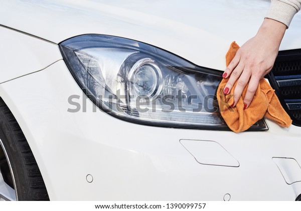 Woman hand clean car headlight with microfiber cloth,\
close up