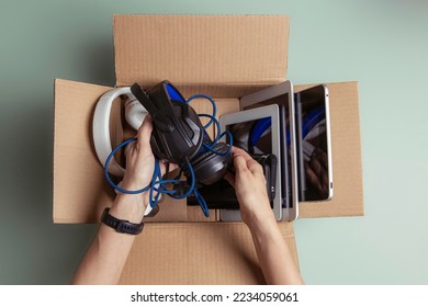 Woman hand collect old used computers, digital tablets, smartphones, electronic devices to cardboard box. Top view. Donation, charity, e-waste, electronic gadgets for reuse, refurbish, recycle concept - Powered by Shutterstock