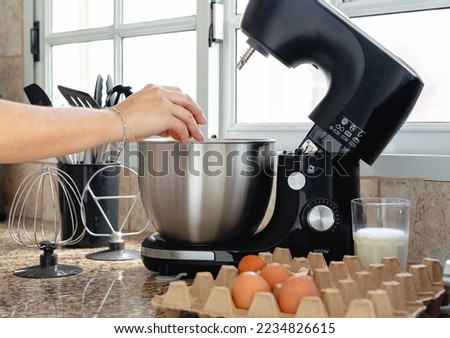 Woman hand cracking an egg inside mixer for making a cake. Close up caption. Unrecognizable person