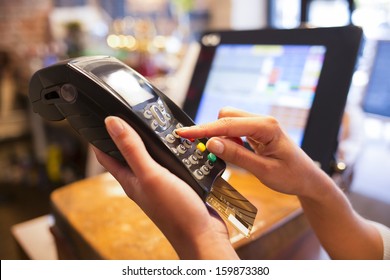 Woman hand with credit card swipe through terminal for sale in restaurant
